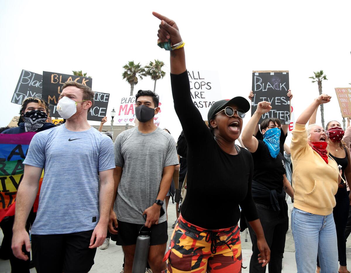 Protesters hold signs during a Black Lives Matter rally at Pier Plaza in Huntington Beach on Saturday.