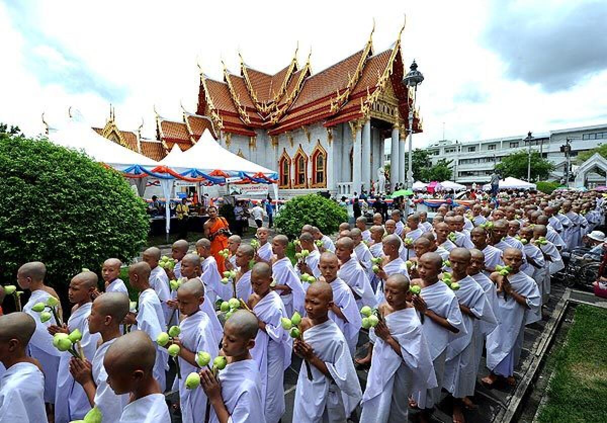 Thai Buddhist novices walk around the Marble Temple, holding lotus flowers and candles, during a ceremony to mark their passage into monkhood in Bangkok, Thailand.