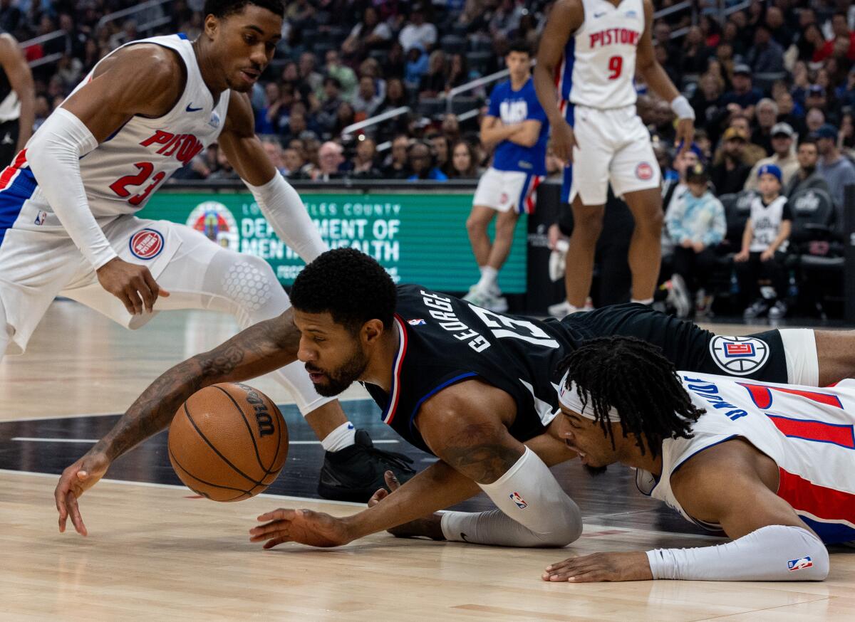 Clippers forward Paul George dives for a loose ball in front of Detroit Pistons guard Stanley Umude.