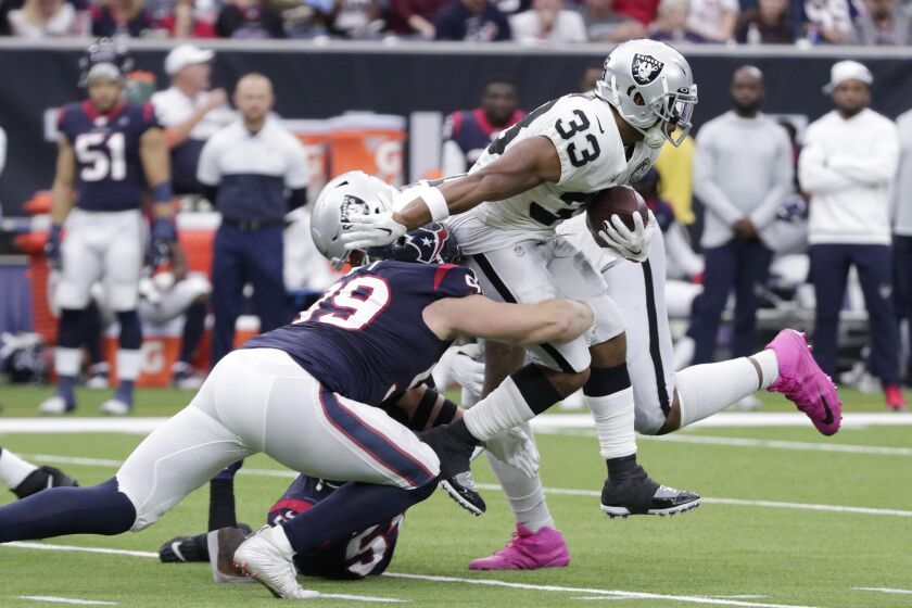 Oakland Raiders running back DeAndre Washington (33) is hit by Houston Texans defensive end J.J. Watt (99) on a run during the first half of an NFL football game Sunday, Oct. 27, 2019, in Houston. (AP Photo/Michael Wyke)