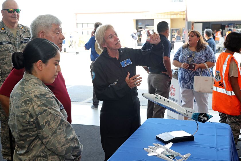 Lt. Col. Dee Chester, center, a Virgin Galactic astronaut, explains a Virgin Galactic flight plan during the Civil Air PatrolOs Remobilization celebration event at AFI Flight Training Center in Fullerton on Saturday.