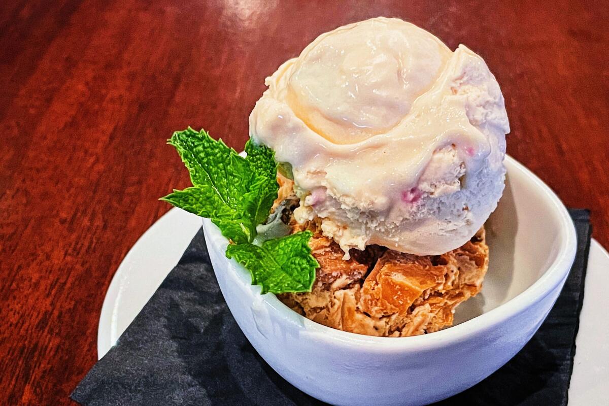 Two scoops of ice cream, birthday cake and peanut butter, in a white cup garnished with mint at Craig's in West Hollywood