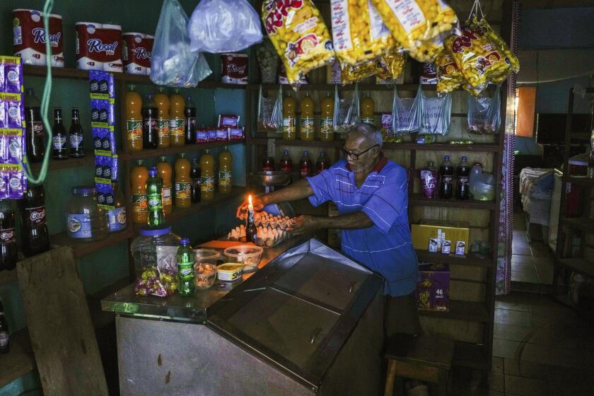 A man lights a candle in his shop during a blackout in Caracas, Venezuela, Friday, Aug. 30, 2024. (AP Photo/Ariana Cubillos)