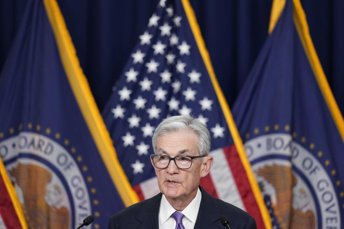 Jerome Powell speaks during a news conference next to a row of flags.