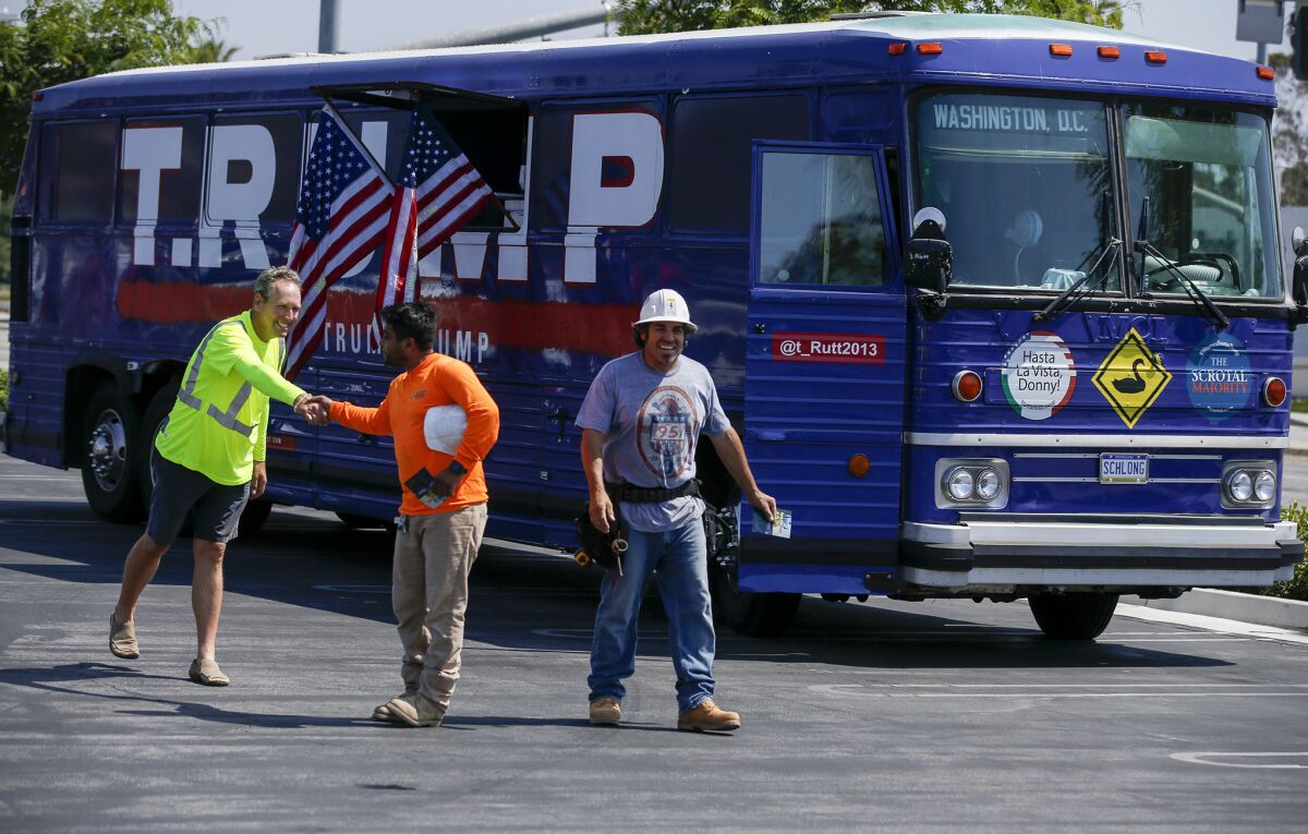 Artist David Gleeson, left, shakes hands with two Trump supporters in the parking lot of a Wal-Mart store in Torrance where he and fellow artist Mary Mihelic parked their bus.