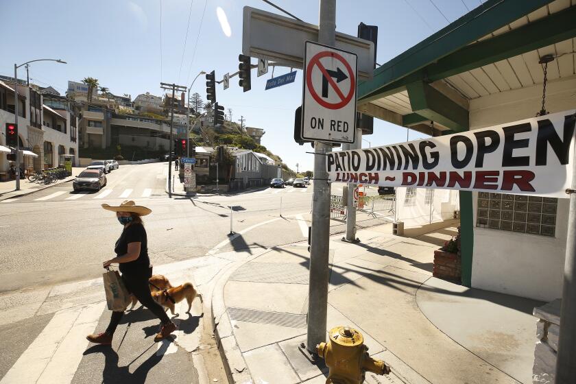 LOS ANGELES, CA - FEBRUARY 22: Resident Petria Seymour walks her dogs Tayto and Volpe through the popular commercial center of Playa Del Rey at Culver Blvd and Vista Del Mar which features restaurants open for outside dinning as this area and Malibu have avoided the COVID winter surge. Playa del Rey on Monday, Feb. 22, 2021 in Los Angeles, CA. (Al Seib / Los Angeles Times).