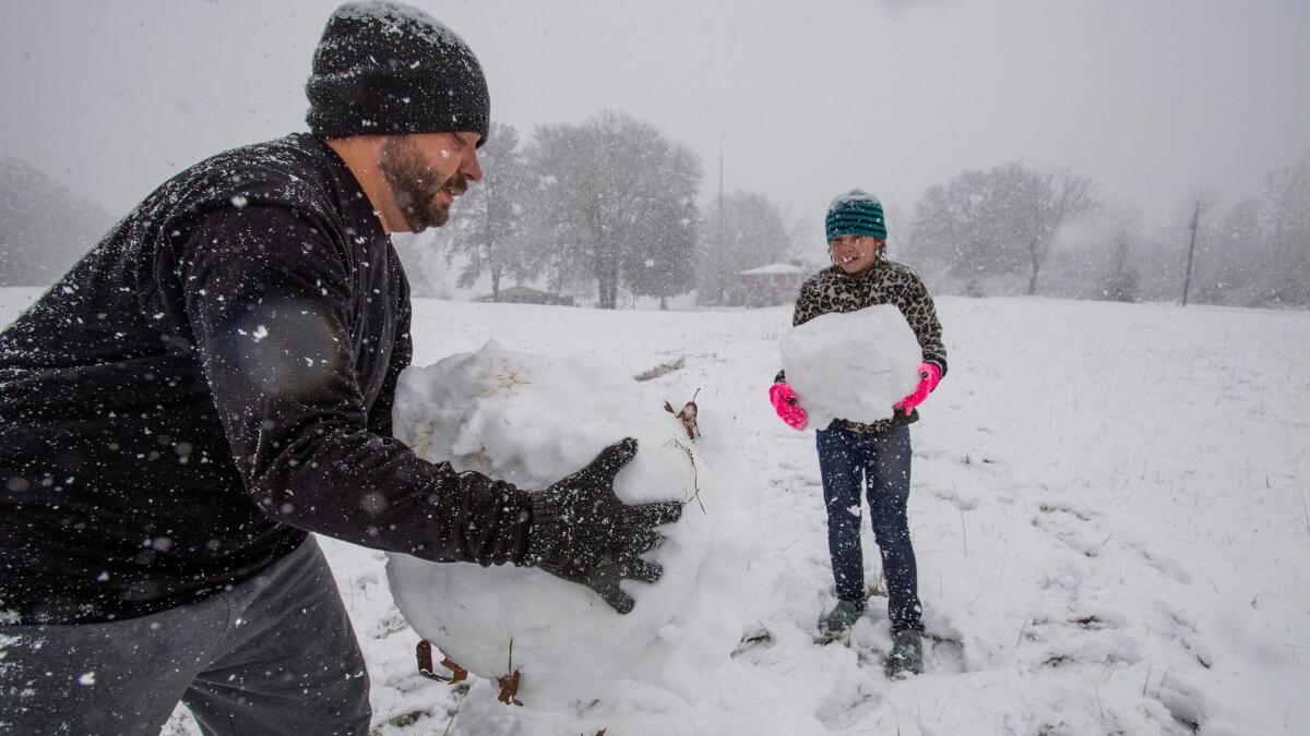 Stephen Fanning and his daughter Addison build a snowman during the heavy snowfall in Clanton, Ala., on Friday.