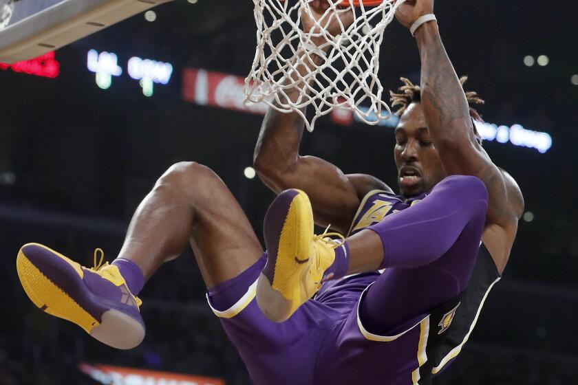 LOS ANGELES, CALIF. - NOV. 13, 2019. Lakers center Dwight Howard hangs on the rim after a slam dunk against the Warrioirs in the second quarter at Staples Center in Los Angeles on Wednesday night, Nov. 13, 2019. (Luis Sinco/Los Angeles Times)