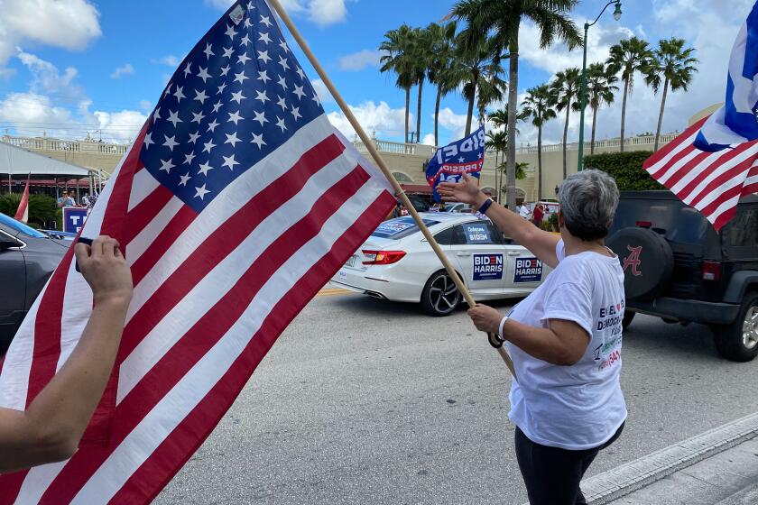 Lourdes Naranjo, waves a American flag during a Biden caravan, October 18, in Miami, Fla. A group of Trump supporters gathered outside of Versailles and both sides shouted at one another.