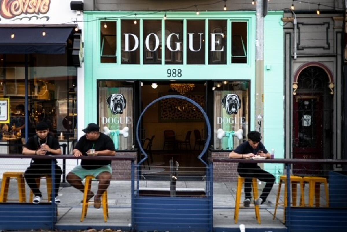 The exterior of a restaurant with the sign "Dogue" and a picture of a dog and a bone.