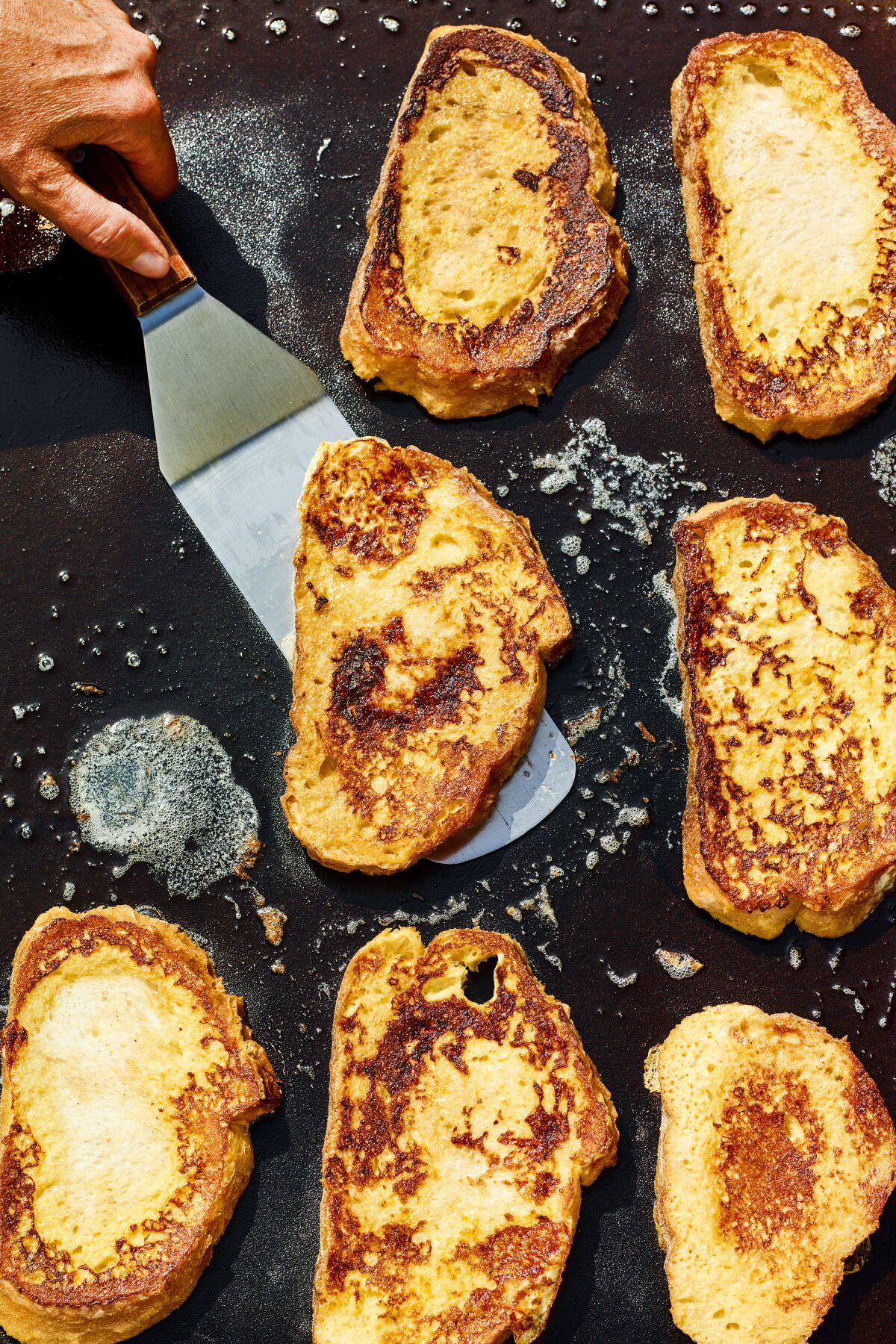 French toast cooks on a flattop outdoor griddle.