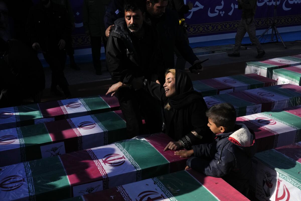 Una mujer llora sobre el ataúd envuelto con una bandera iraní de su ser querido que murió