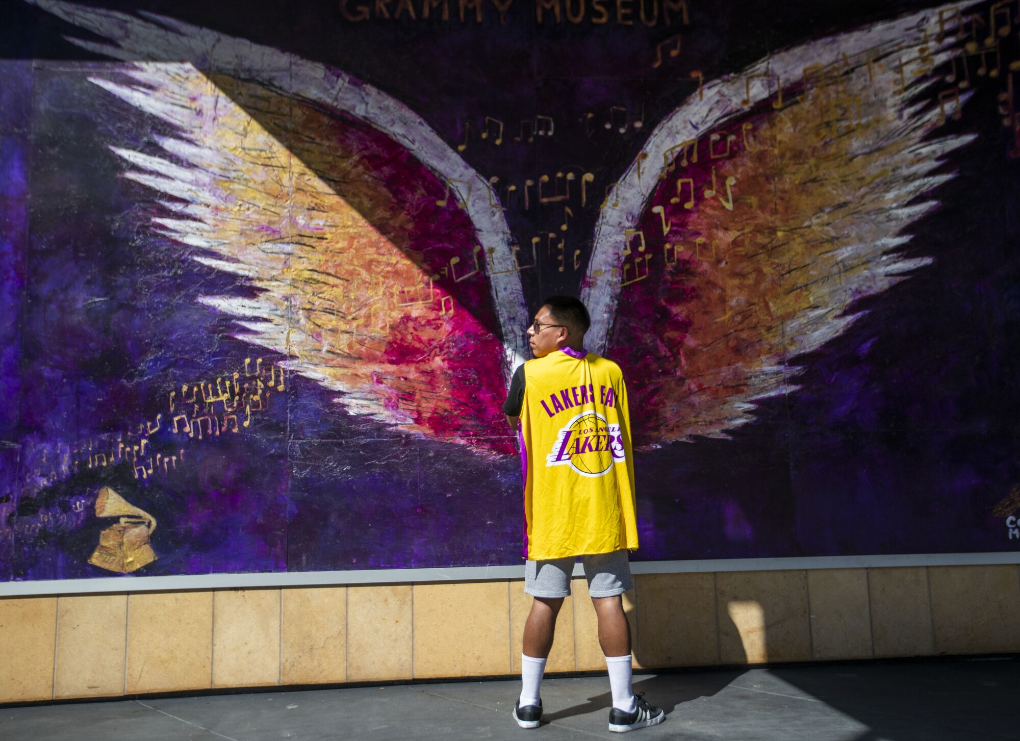 Lakers fan Emanuel Pascual, of Alhambra, takes a photo in front of a mural outside the Grammy Museum at L.A. Live.