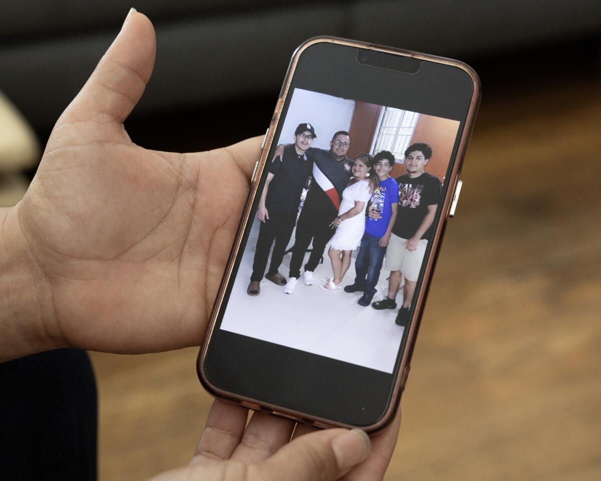 A photo displayed on a cellphone shows a man and a woman, flanked by three children.