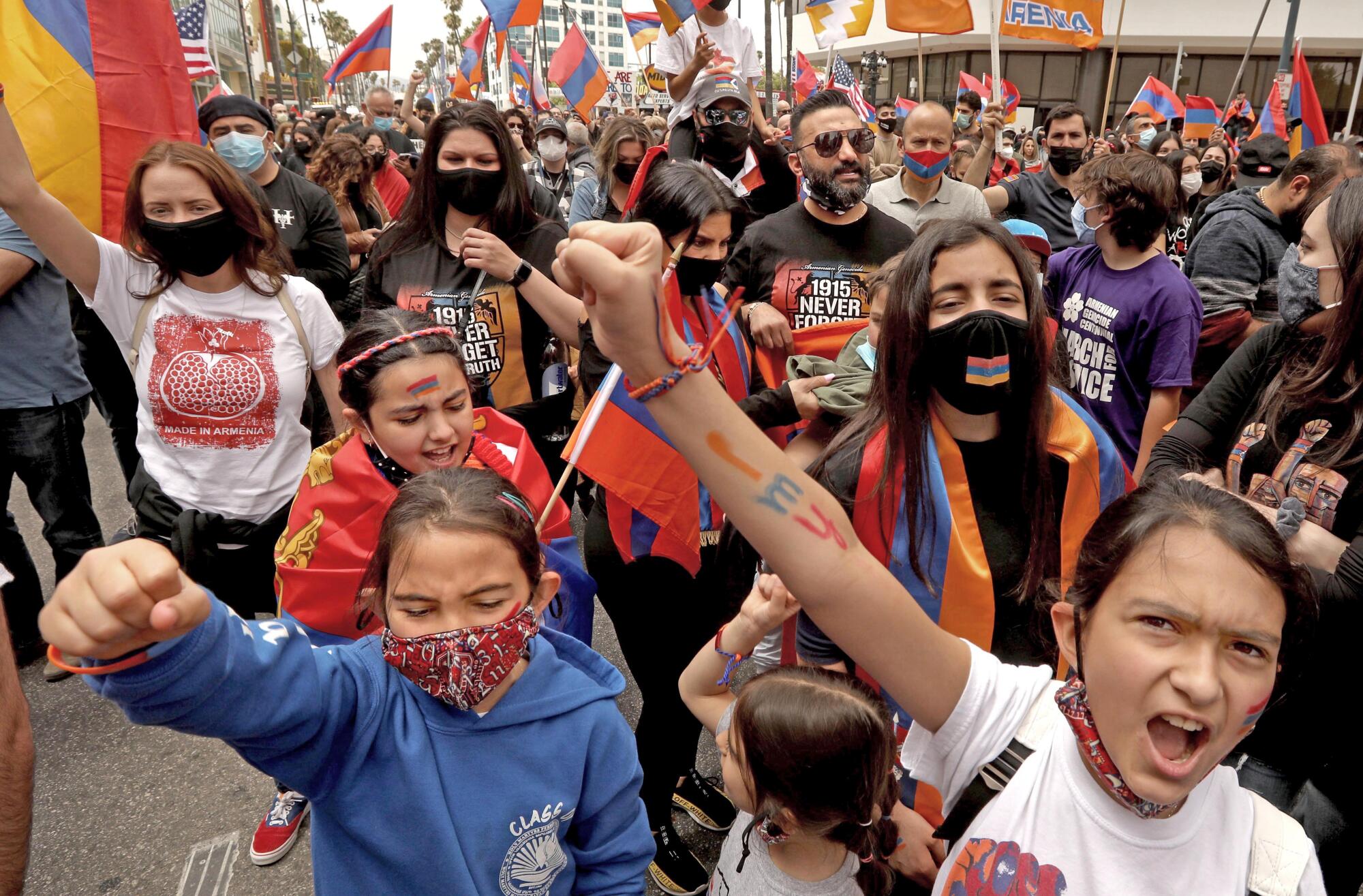 Daisy Kalaydjian, left, and her sister Izabella raise defiant fists while joining hundreds from the Armenian community.
