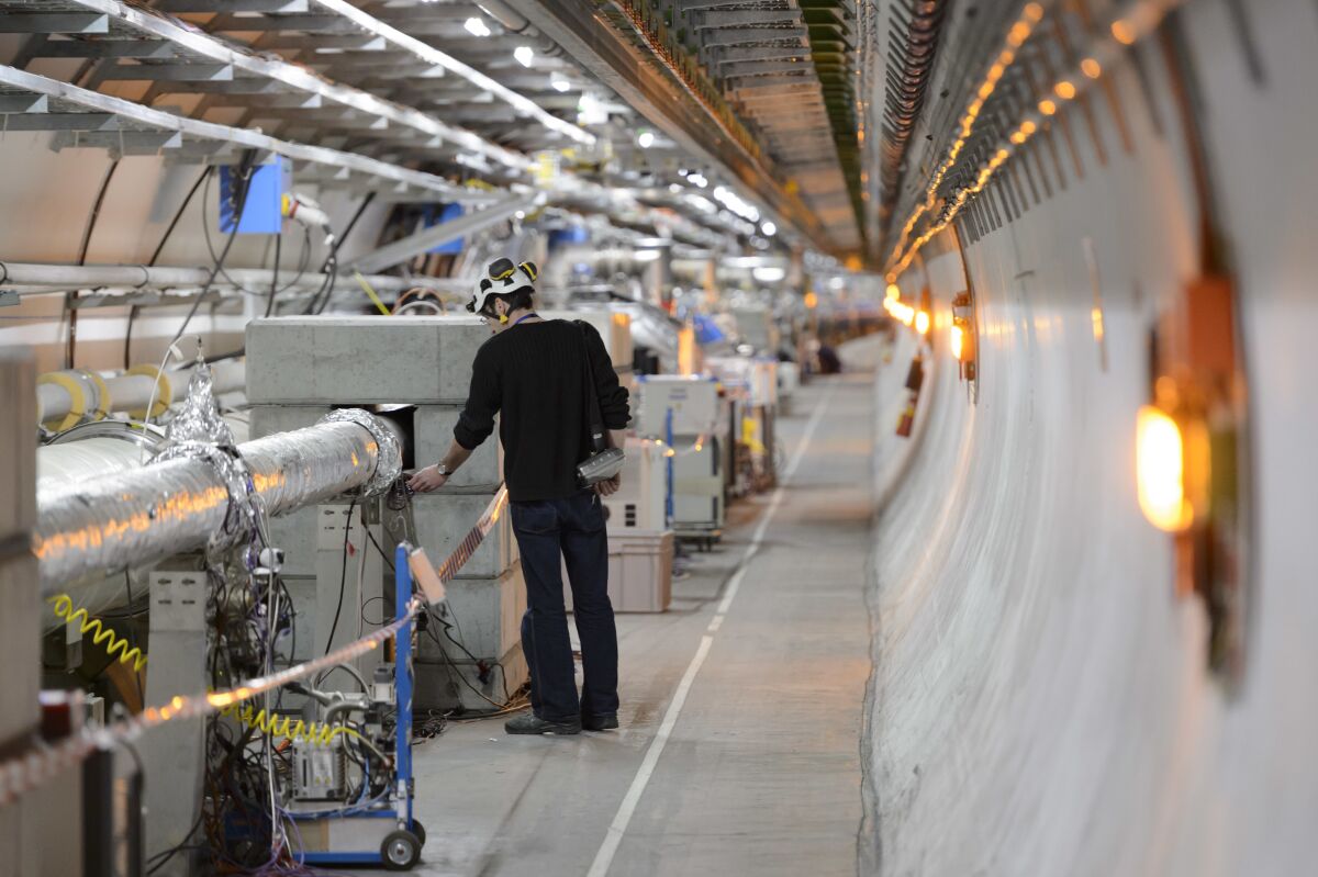 FILE - A technician works in the LHC (Large Hadron Collider) tunnel of the European Organization for Nuclear Research, CERN, during a press visit in Meyrin, near Geneva, Switzerland, Feb. 16, 2016. The physics lab that’s home to the world’s largest atom smasher announced on Tuesday, July 5, 2022 the observation of three new “exotic particles” that could provide clues about the force that binds subatomic particles together. The observation of a new type of pentaquark and the first duo of tetraquarks at CERN, the Geneva-area home to the LHC, offers a new angle to assess the so-called “strong force” that holds together the nuclei of atoms. (Laurent Gillieron/Keystone via AP, file)