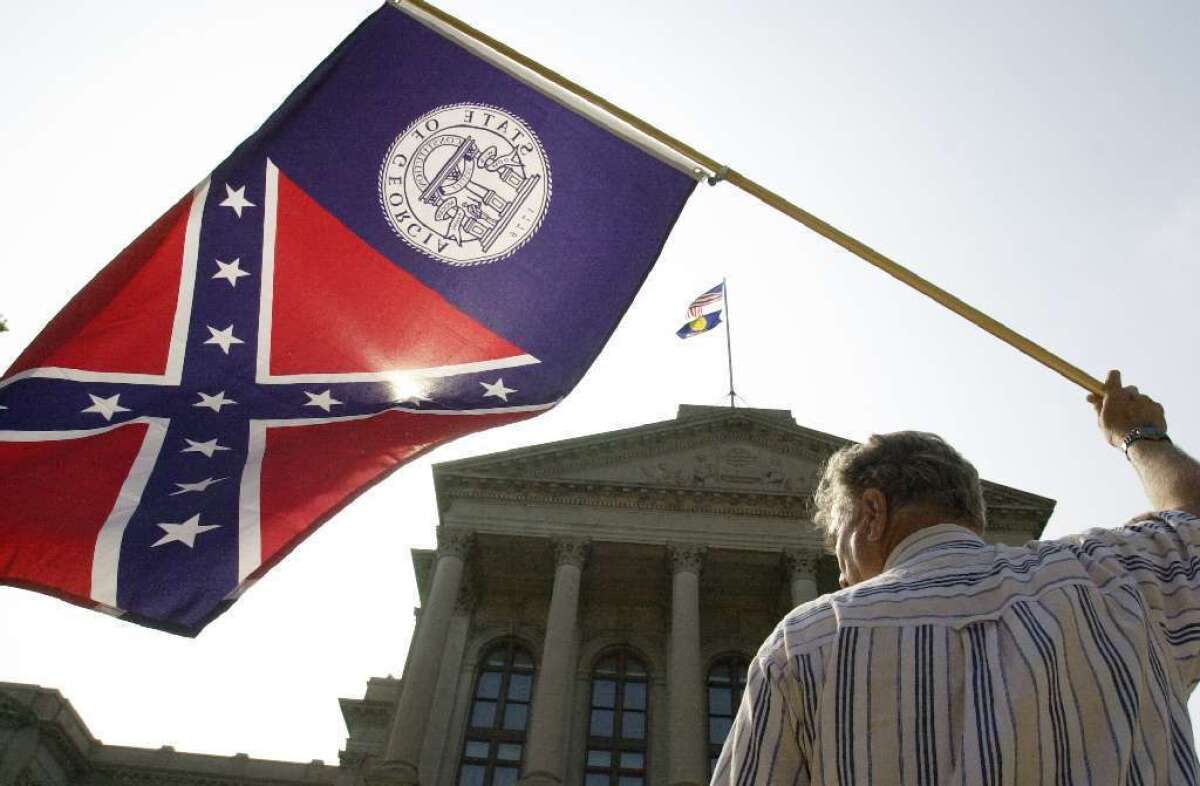 A man waives Georgia's former state flag, which ceased to be the state's official banner after the state legislature passed a measure banning the old design, which bears the Confederate cross.