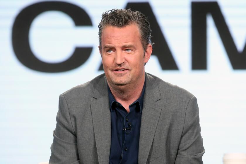 Matthew Perry in a gray suit and dark shirt in 2017