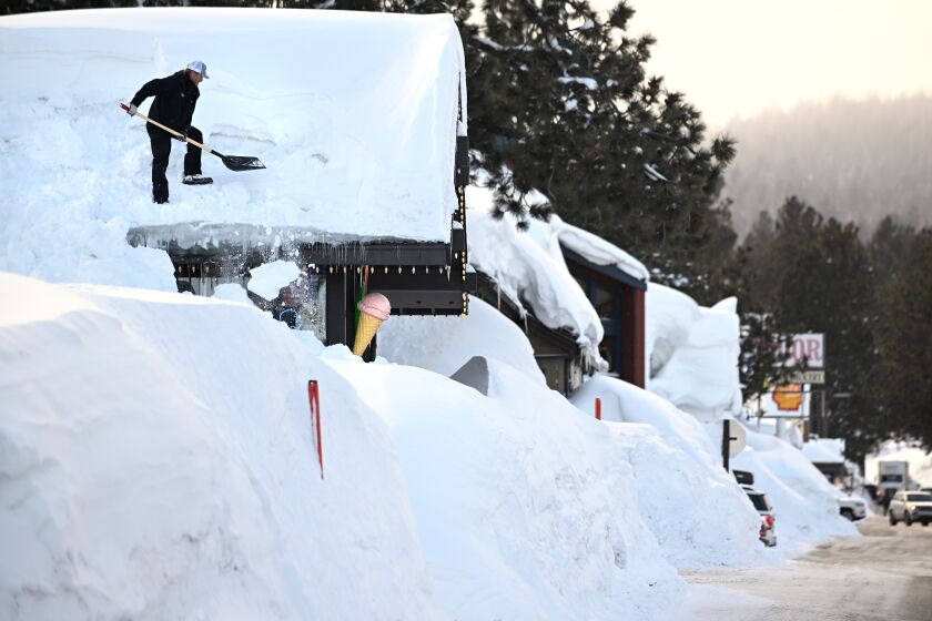 Mammoth Mountain California March 7, 2023-Owner Brang Miller shovels snow off the roof of Mammoth Fun Shop and locals try to dig out in between storms. Over 550 inches of snow has fallen at the main lodge as residents try to dig out. (Wally Skalij/(Los Angeles Times)