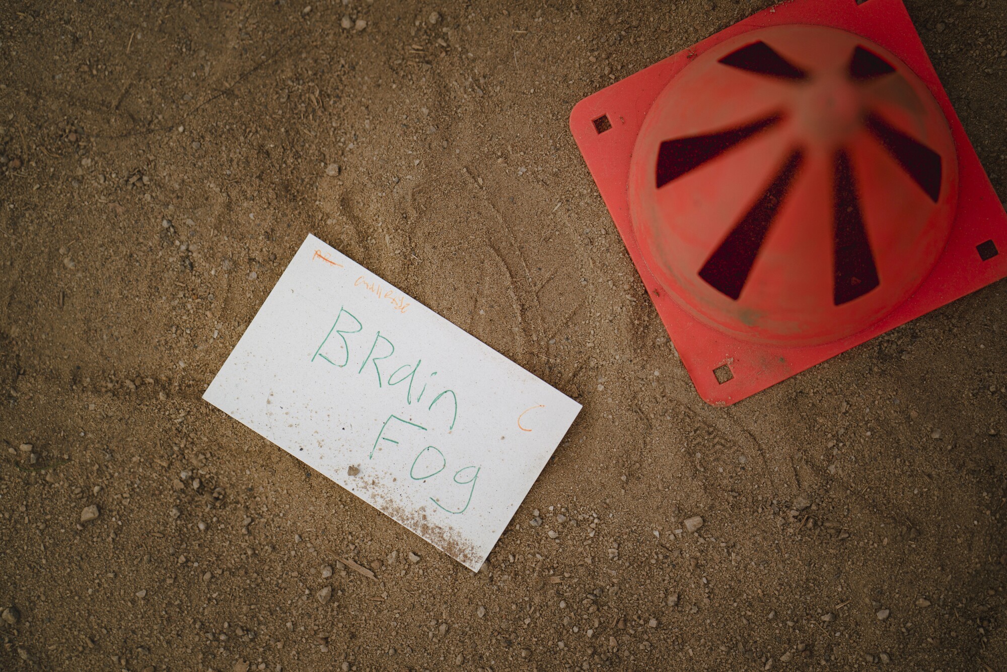 A card with the words 'brain fog' lies on a dirt floor.