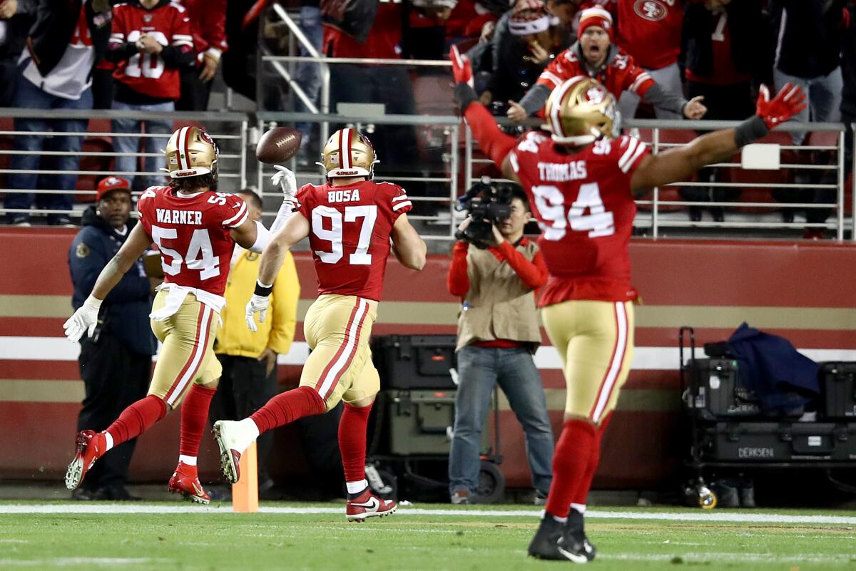 49ers linebacker Fred Warner flips the ball in the end zone after returning an interception 46 yards for a touchdown late in the second quarter.