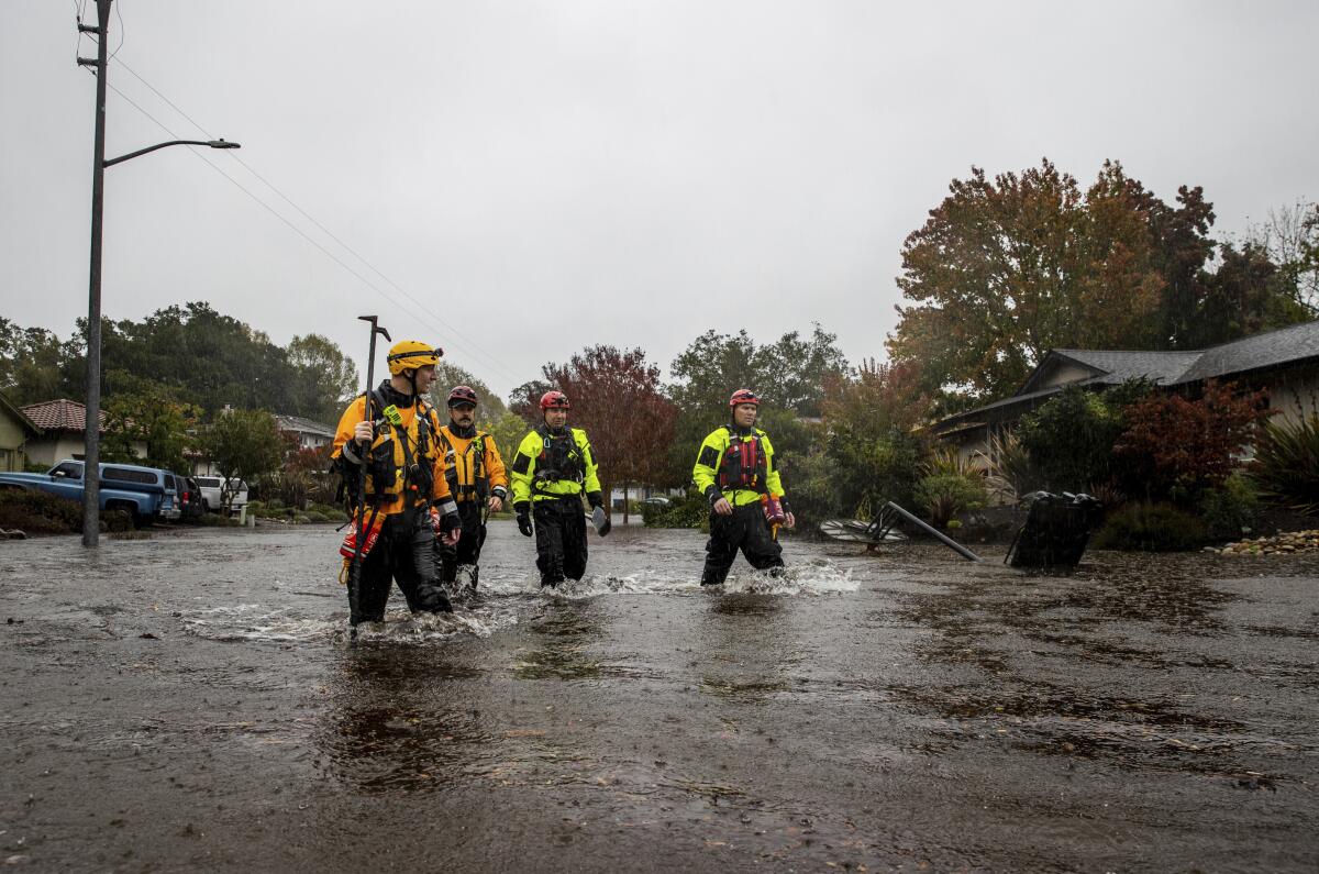 Four firefighters walk in knee-deep water