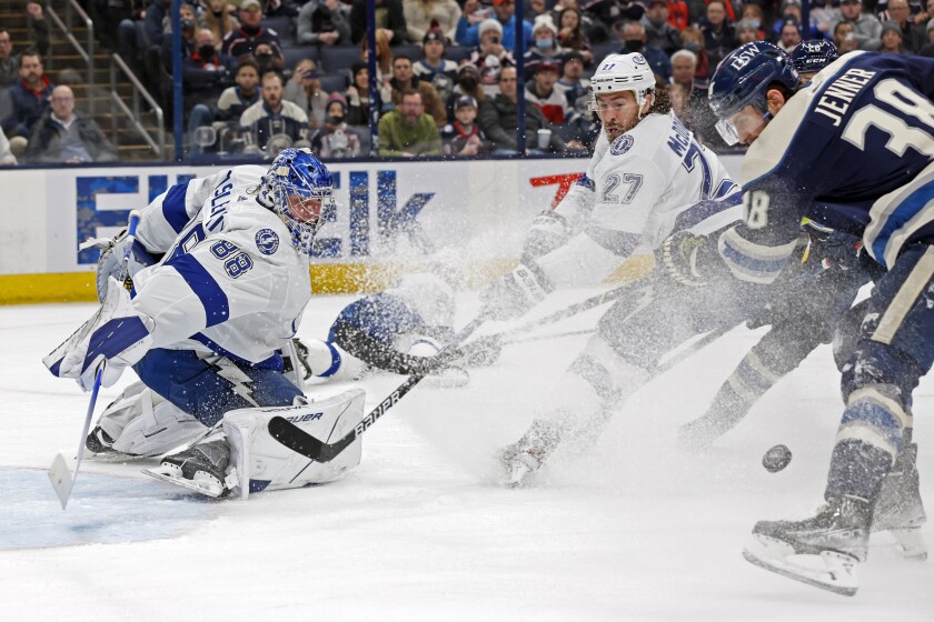 Tampa Bay Lightning's Andrei Vasilevskiy, left, makes a save as teammate Ryan McDonagh, center, and Columbus Blue Jackets' Boone Jenner try to control the puck during the second period of an NHL hockey game Tuesday, Jan. 4, 2022, in Columbus, Ohio. (AP Photo/Jay LaPrete)