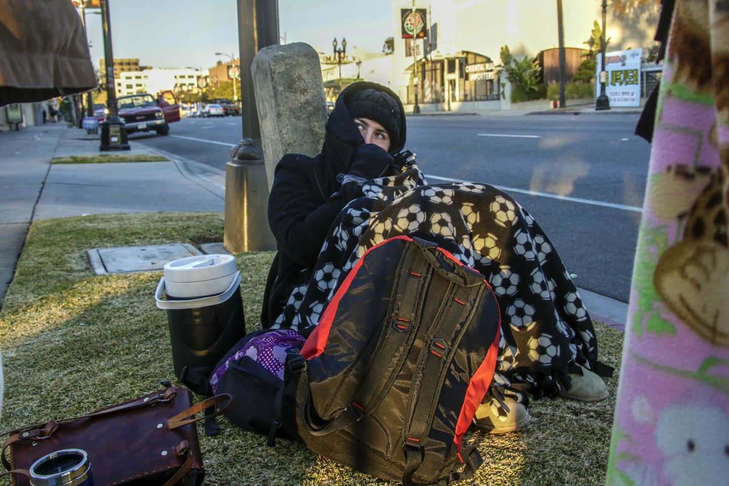 Jamie Hearn, all bundled up to beat early morning cold, holds a spot along Colorado Boulevard prior to the Rose Parade.