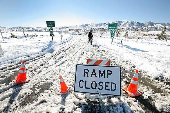 Grounded motorist Mike Cerrato walks up the Avenue S onramp to the southbound 14 Freeway in Palmdale. Heading home to Santa Clarita from Mammoth, he was stranded in Mojave overnight. Commuters' hopes rise with temperatures » Your Scene: SoCal Snow | Submit photos »