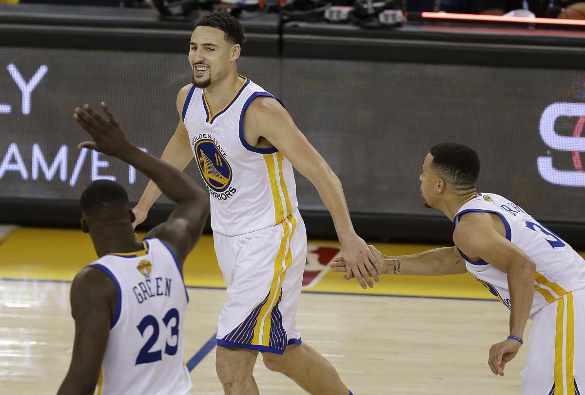 Golden State guard Klay Thompson, center, celebrates with forward Draymond Green (23) and guard Stephen Curry.