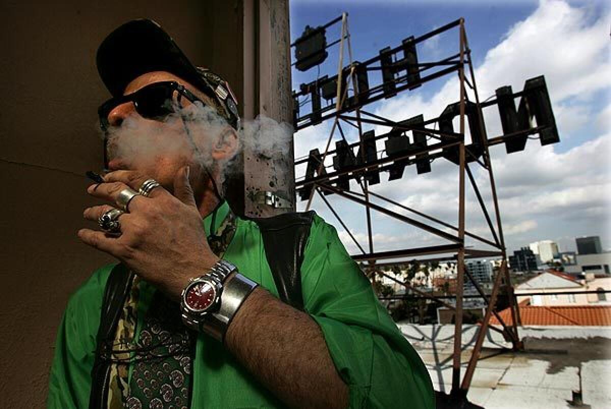 Richard Eastman, assistant manager of the Normandie Hotel, smokes a medical marijuana cigarette near the historic hotel's rooftop sign.