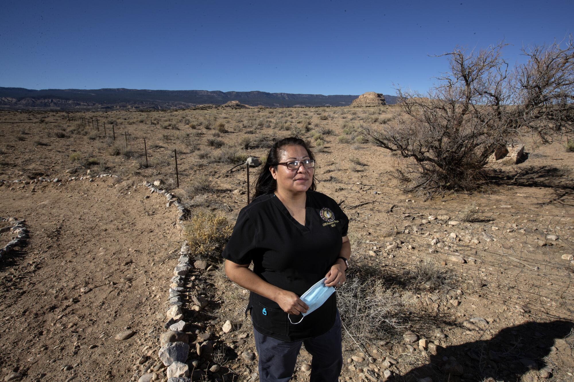 Marlene Montoya stands near a dirt road with open land in the background.