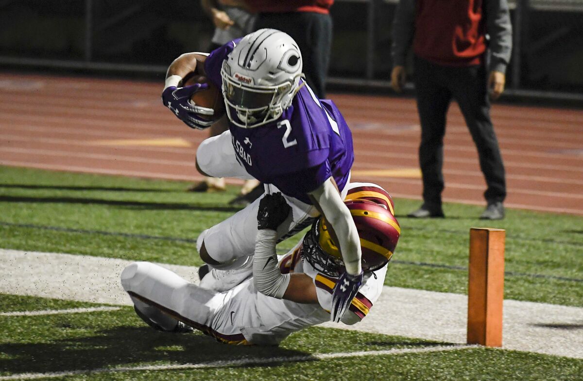 Carlsbad's Matt Moore gets into the end zone past Torrey Pines Ryan Flather in Friday's Open semifinal won by the Lancers.