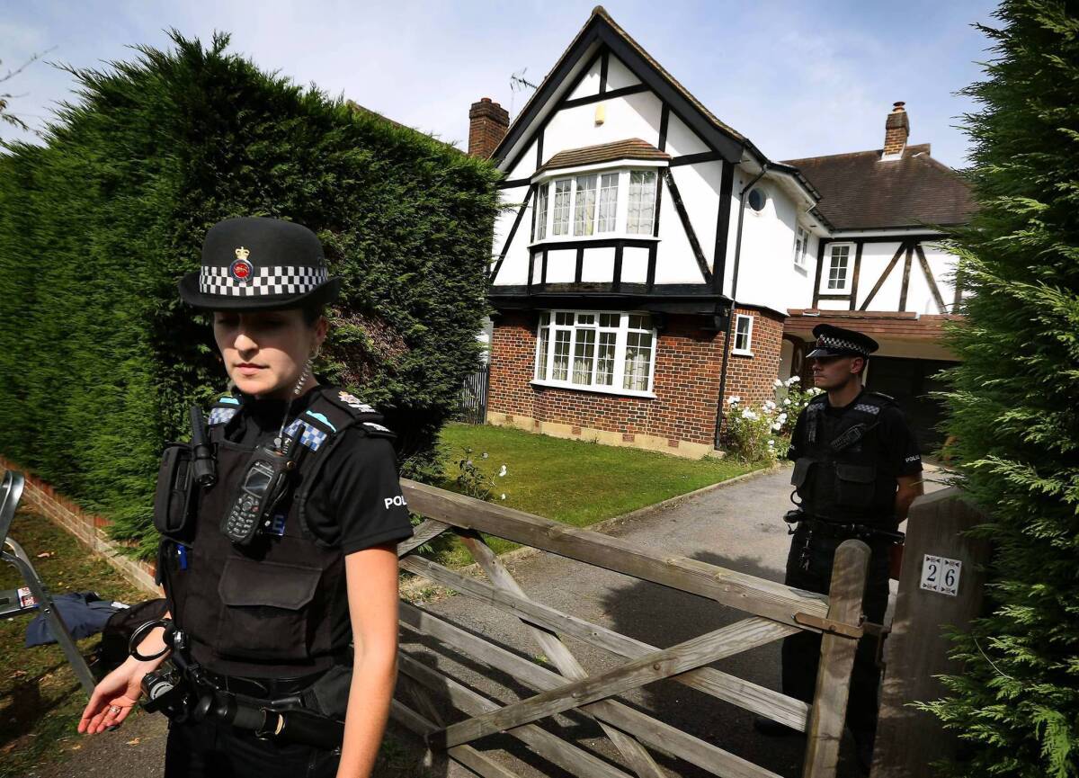 Police are deployed at a home in Surrey, England, said to be the residence of Saad Hilli, the owner of a car in which three people were found shot to death in France.