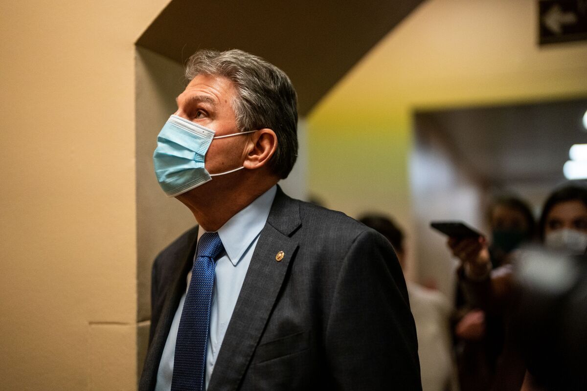 Sen. Joe Manchin, wearing a mask, waits for an elevator at the Capitol