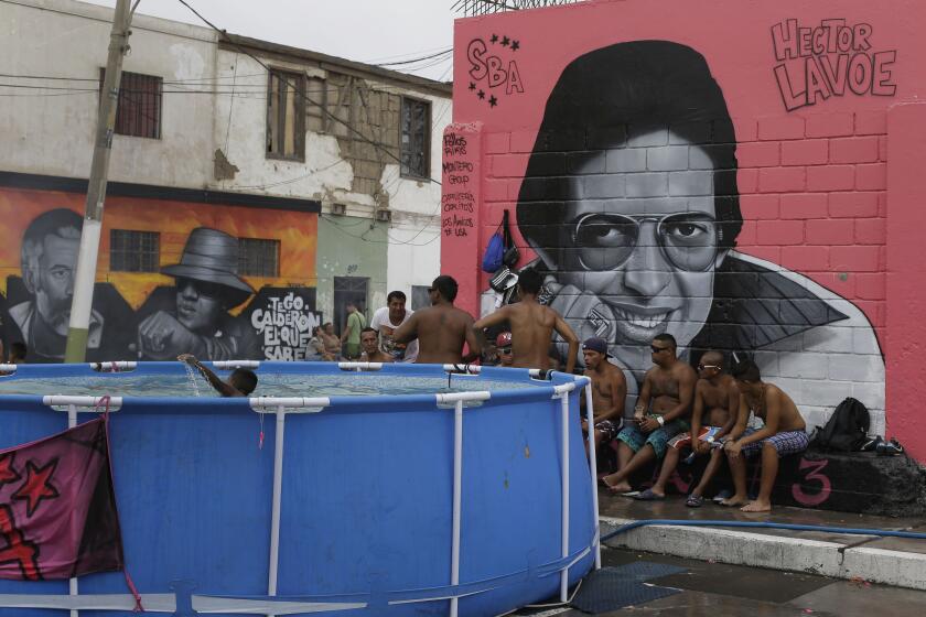 Un grupo de amigos comparten rodeado por un mural con el cantante de salsa Héctor Lavoe, en Callao, Perú.