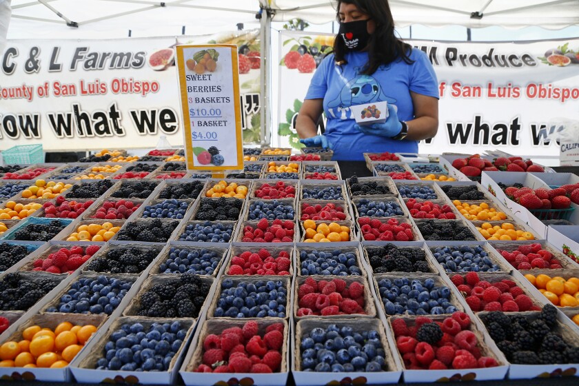 A vendor sells berries at a farmers market at the Orange County fairgrounds in 2021. 