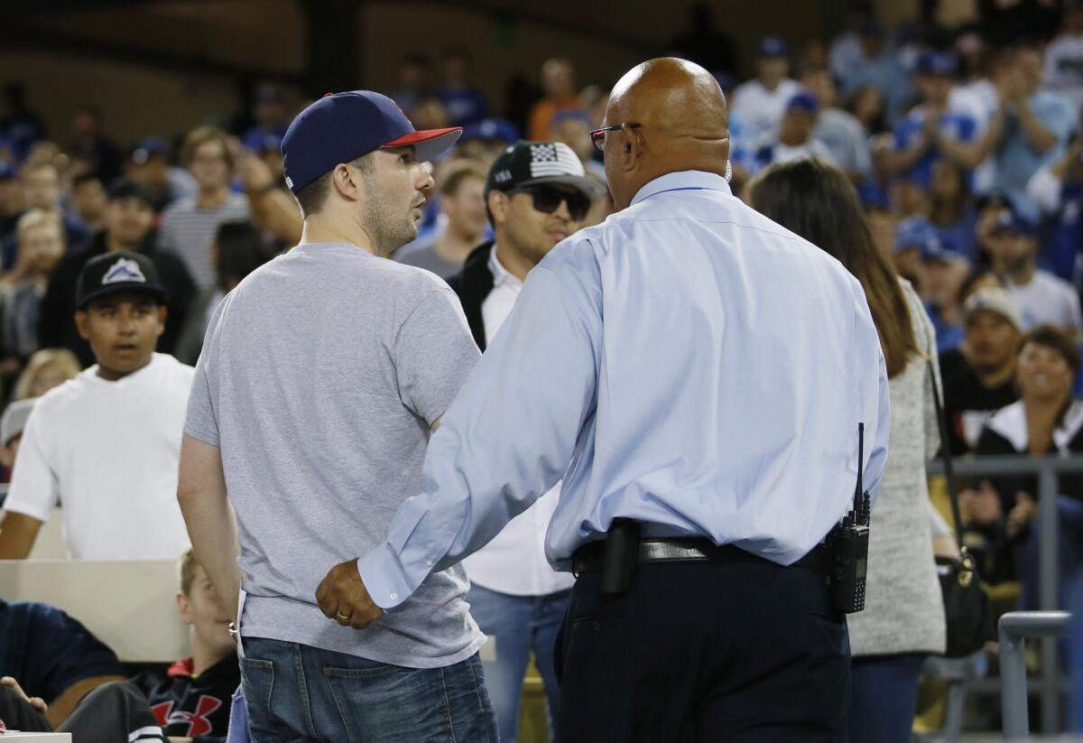 A fan who was sitting in the front row is escorted from his seat by stadium security after Dodgers first baseman Adrian Gonzalez caught a foul ball for an out near his seat during the fifth inning.