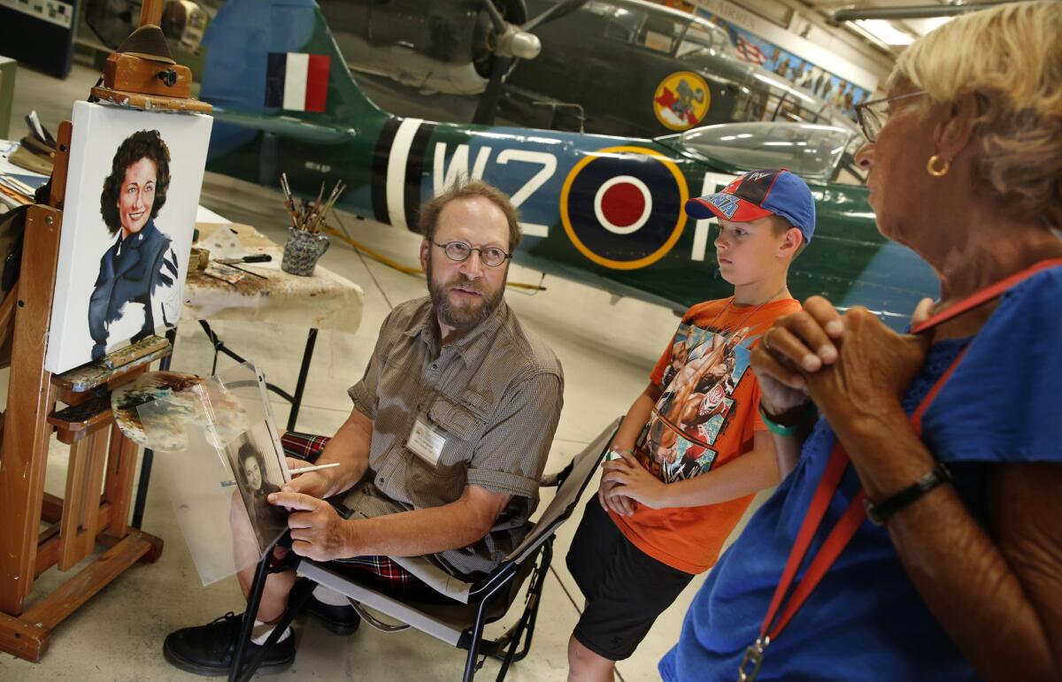 At the Palm Springs Air Museum, artist Chris Demarest talks with museum visitors Lenore Crilly and her grandson Ethan Jordan.
