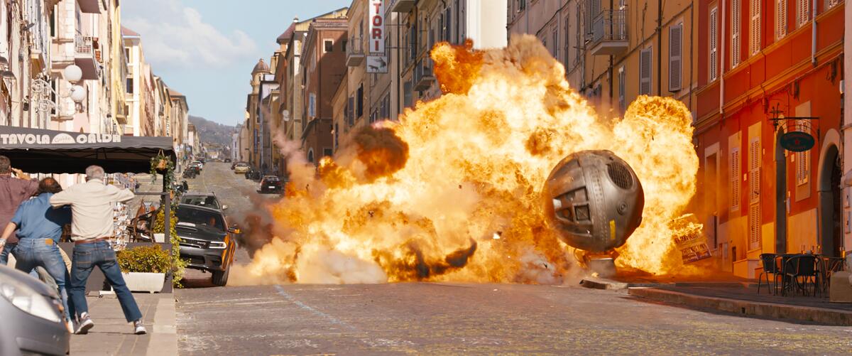 Flames and debris from an explosion spread down a street on a movie shoot.