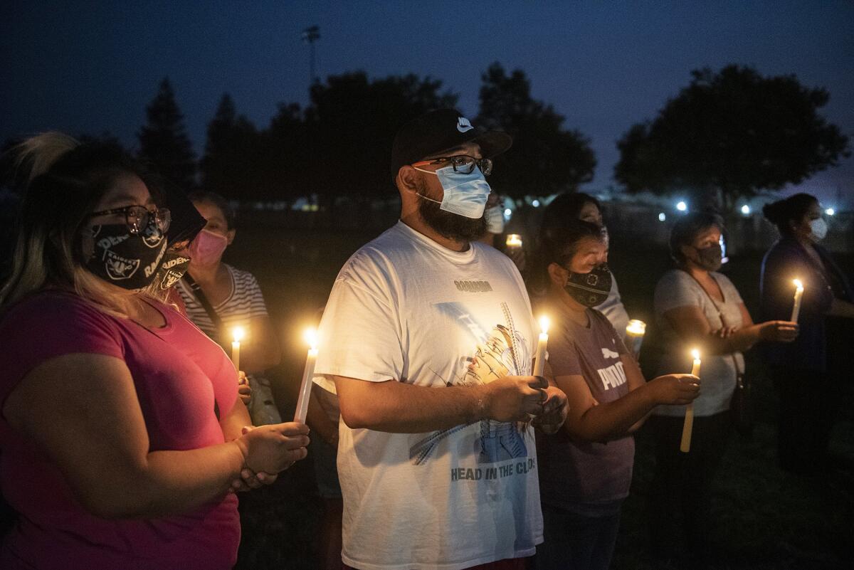 A row of people in masks holding candles at night