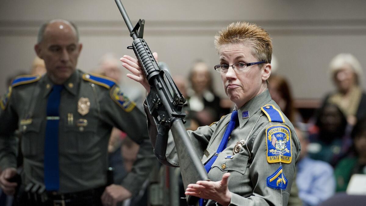 Det. Barbara J. Mattson of the Connecticut State Police holds a Bushmaster rifle during a hearing in Hartford, Conn., in 2013.