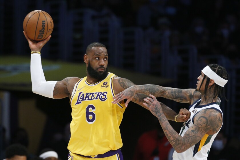 LeBron James (6), de los Lakers de Los Ángeles, busca un pase ante la presión de su rival del Jazz de Utah Jordan Clarkson (derecha), durante la primera mitad del juego de la NBA que enfrentó a ambos equipos, en Los Ángeles, el 17 de enero de 2022. (AP Foto/Ringo H.W. Chiu)