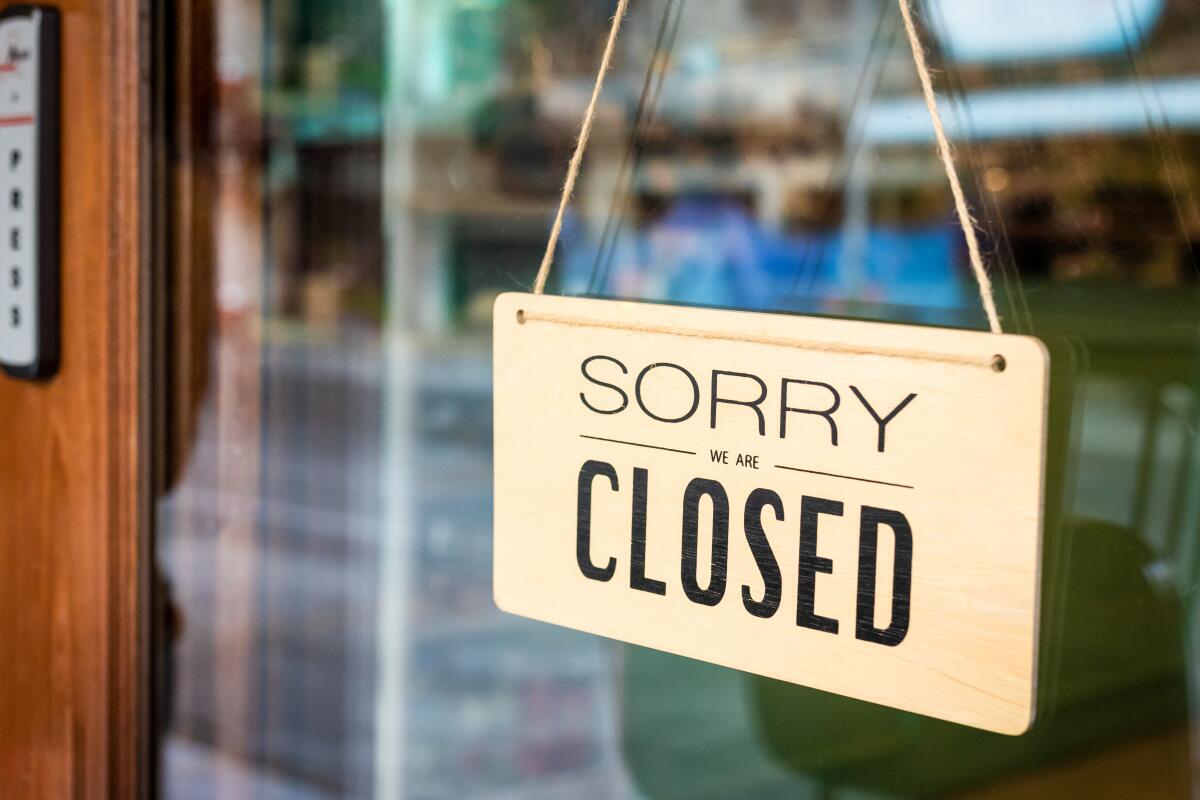 "Sorry we are closed" sign board hangs on a door of a cafe.