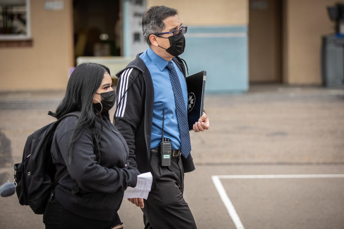 Perkins K-8 Principal Fernando Hernandez, walks Alyssa Garcia to her classroom on Monday in San Diego.