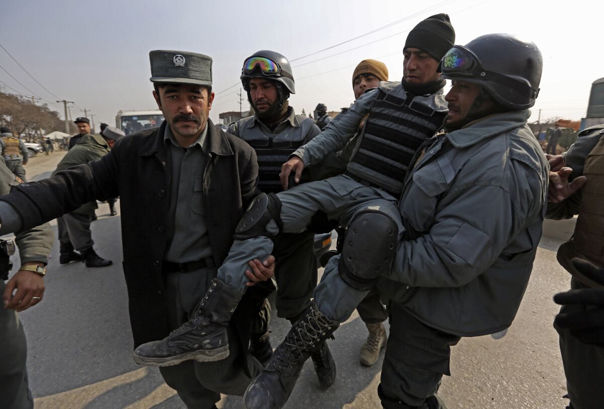 Afghan police carry an injured colleague after a clash with protesters in Kabul.