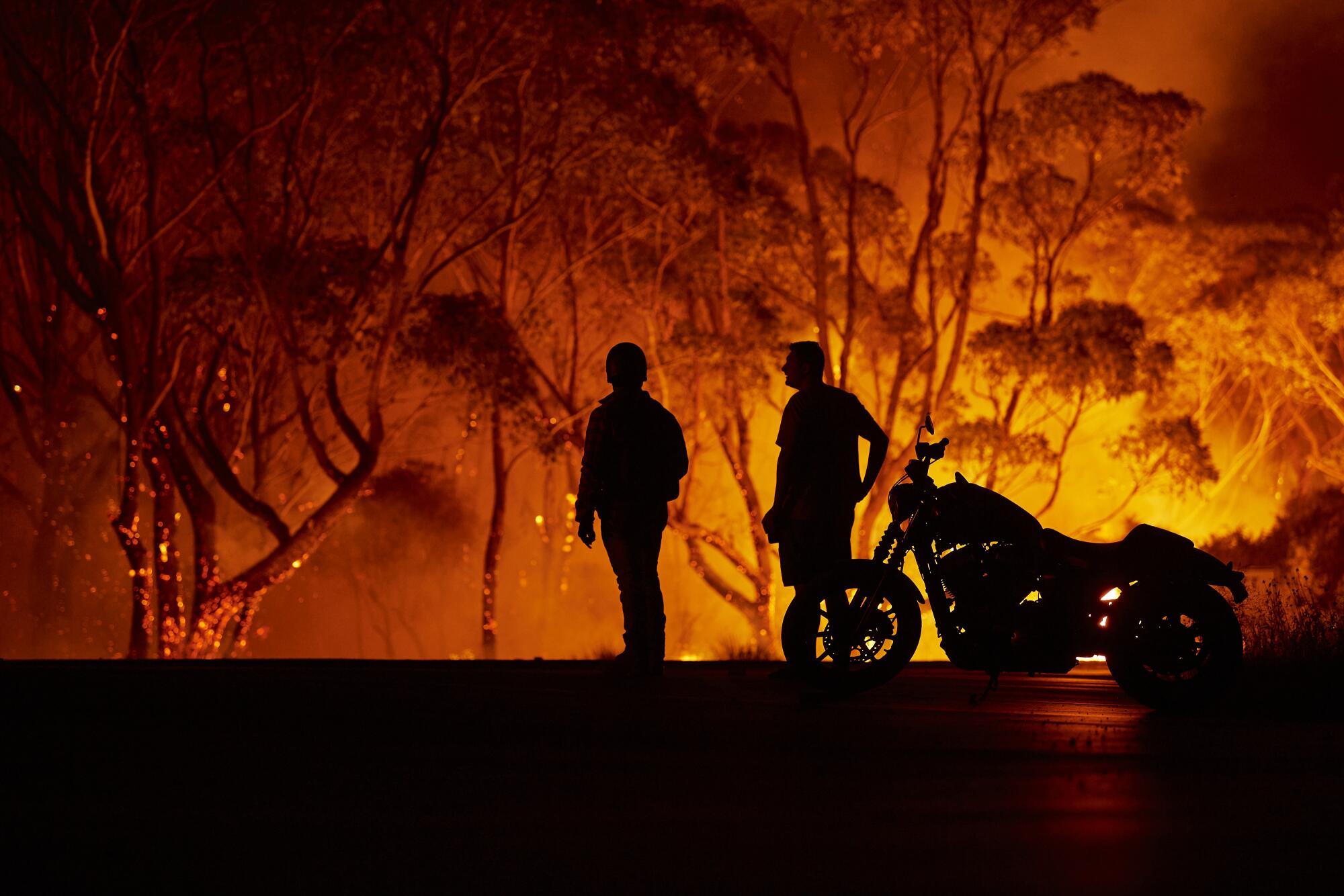 Residents watch as flames burn through bush in Lake Tabourie, Australia.