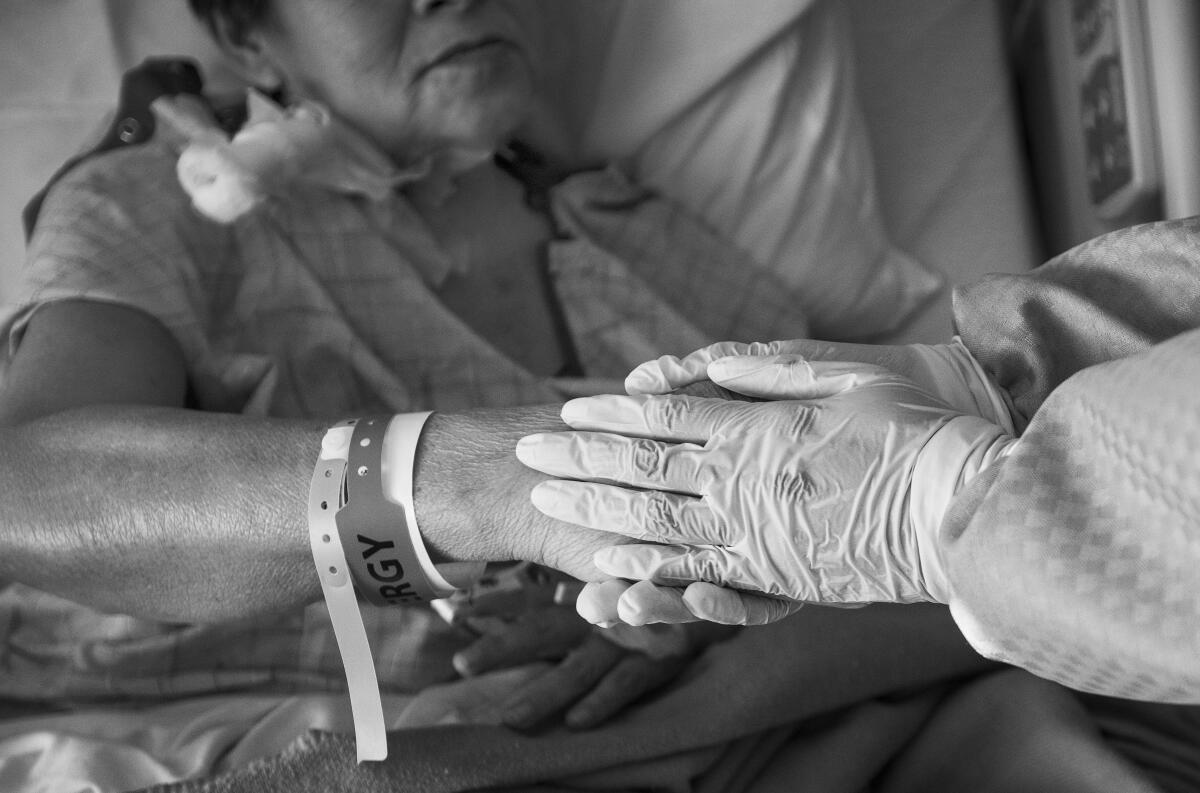 Dr. Maita Kuvhenguhwa, infectious disease specialist at Martin Luther King Jr. Community Hospital, holds Maria Cuellar's hand