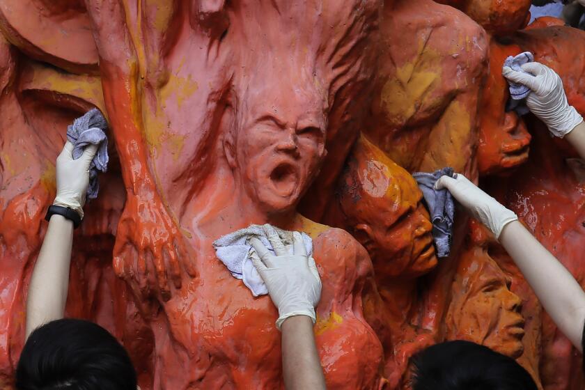 File-University students clean the "Pillar of Shame" statue, a memorial for those killed in the 1989 Tiananmen crackdown, at the University of Hong Kong Tuesday, June 4, 2019. A monument at a Hong Kong university that commemorated the 1989 Tiananmen massacre was boarded up by workers late Wednesday, Dec. 22, 2021, prompting fears over the future of the monument as the city's authorities crack down on dissent. (AP Photo/Kin Cheung, File)