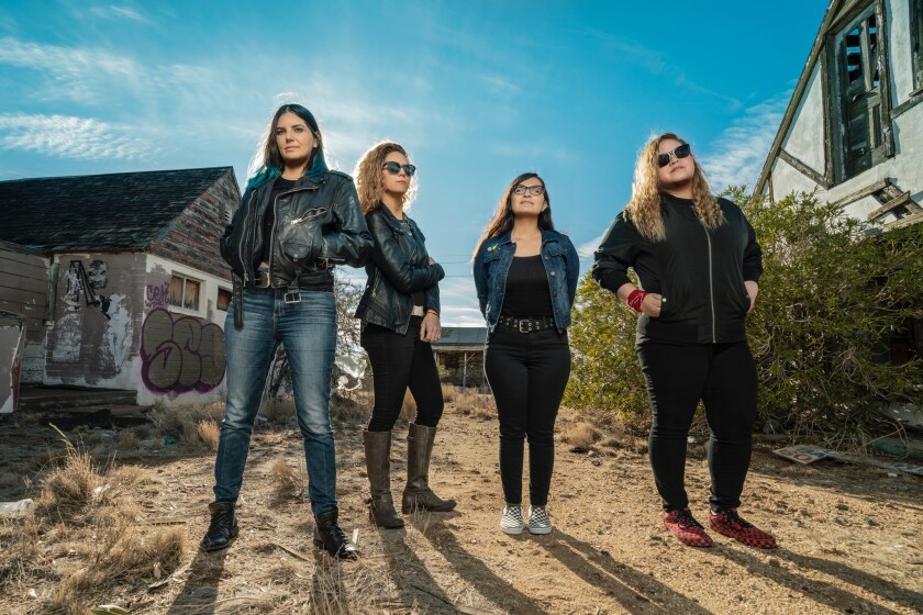 Four women stand in front of buildings.